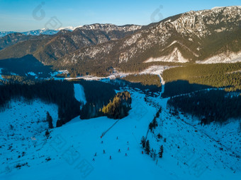 冬天斯洛伐克阳光明媚的一天的明亮滑雪度假胜地蓝色的天空山山峰和滑雪山坡上空中视图冬天山山峰和滑雪山坡上阳光明媚的天气空中视图