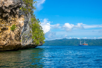 印尼岩石海岸热带岛阳光明媚的天气热带雨林坡游艇的距离岩石海岸与热带雨林和游艇的距离