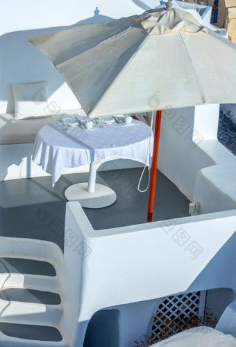 希腊阳光明媚的夏天一天的火山口圣托里尼岛岛服务表格下太阳伞的户外阳台大太阳伞和服务表格