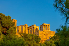 希腊雅典夏天万里无云的天空和日落光入口的卫城包围松分支机构入口的卫城的日落