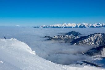 蓝色的天空和阳光明媚的天气在的雪山峰的山谷是密集的雾孤独的旅游照片的美雪山峰和雾的山谷