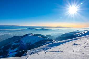 冬天斯洛伐克滑雪度假胜地明亮视图从的前的白雪覆盖的山的滑雪坡与滑雪者滑雪坡和冬天太阳在山山峰