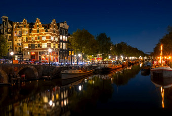 荷兰晚上运河阿姆斯特丹和万里无云的天空住宅驳船和船是停泊与反射的水阿姆斯特丹运河与船万里无云的晚上