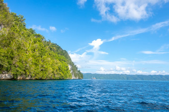 岩石海岸的热带岛印尼阳光明媚的天气热带<strong>雨林</strong>的坡游艇距离阳光明媚的岩石海岸与热带<strong>雨林</strong>和游艇的距离