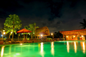 晚上池热带酒店棕榈树雨伞太阳便鞋和酒吧晚上游泳池与酒吧热带酒店