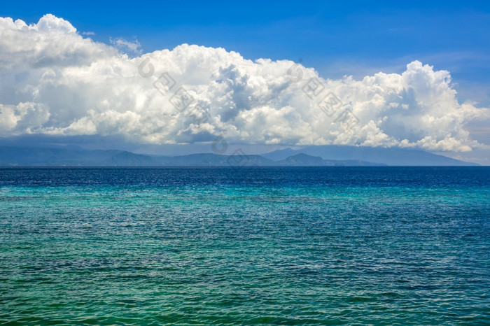 印尼阳光明媚的一天绿松石水平静海洋令人惊讶的是美丽的云在遥远的岛绿松石海水和令人惊异的云在的岛