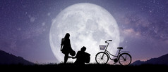 轮廓晚上景观夫妇情人跳舞和唱歌的山与乳白色的道路背景在的完整的月亮