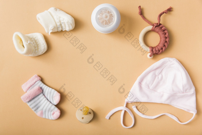 婴儿袜子一对羊毛鞋子奶嘴帽牛奶瓶玩具橙色背景决议和高质量美丽的照片婴儿袜子一对羊毛鞋子奶嘴帽牛奶瓶玩具橙色背景高质量美丽的照片概念