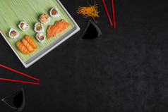开销视图寿司卷与磨碎的胡萝卜红色的筷子对黑色的背景