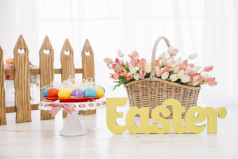 色彩斑斓的复活节鸡蛋<strong>郁金香</strong>篮子与黄色的复活节文本木桌子上