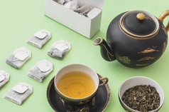 Herbal茶袋茶杯苍白的绿色纸背景