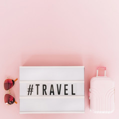 标签与旅行文本lightbox与太阳镜微型旅行袋粉红色的背景