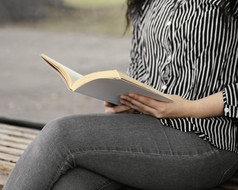 年轻的女人阅读有趣的书在户外