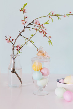色彩鲜艳的复活节鸡蛋附近花嫩枝花瓶与水碗