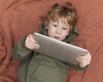 前视图年轻的男孩使用平板电脑床上