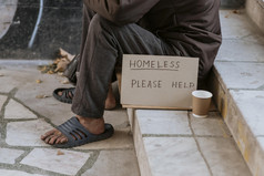 前面视图无家可归的人男人。楼梯与帮助标志杯