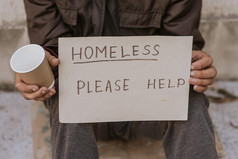 无家可归的人男人。持有杯帮助标志