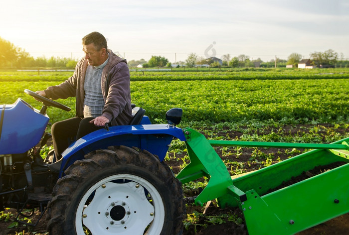 农民驱动器拖拉机在农场场收获第一个土豆早期春天农业和农田农业行业和农业综合企业收获机械化发展中国家农场支持