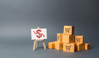 桩纸板盒子和站与红色的下来箭头下降的生产货物和产品的经济经济低迷和经济衰退下降消费者需求下降价格较低的利润