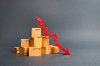 桩纸板盒子和红色的箭头下来的下降的生产货物和产品的经济经济低迷和经济衰退下降消费者需求下降出口进口