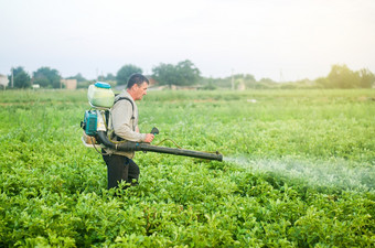 农民与雾喷雾器鼓风机流程的土豆种植园从害虫和真菌感染保护和哪烟熏器雾化器使用农业工业化学物质保护作物