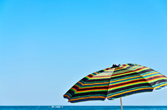 色彩斑斓的伞对的蓝色的天空而且的海地平线