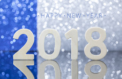 新一年白色木数字反射玻璃表格前面的蓝色的和银灯散景