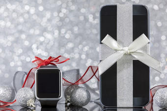 智能手机和智能手表和装饰为圣诞节树黑色的玻璃表格焦点智能手机