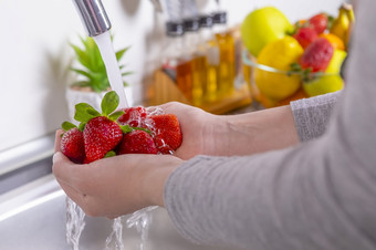女人手洗草莓的厨房吃新鲜的和健康的水果概念特写镜头