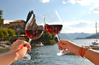 两个葡萄酒杯的手瓦伦纳小镇的湖作为意大利