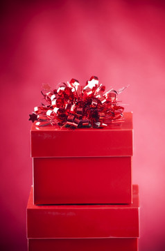 明亮的红色的礼物盒子与装饰模糊红色的背景