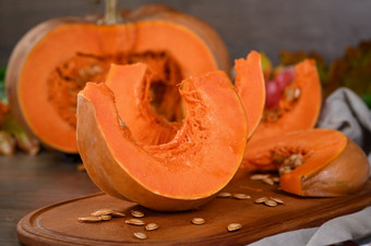 整个新鲜的橙色大南瓜和片南瓜木董事会特写镜头有机蔬菜产品成分为烹饪健康的食物素食主义者