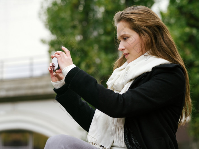 照片美丽的女人使用她的智能手机取照片照片从的照片漫步柏林在微量库存世博会