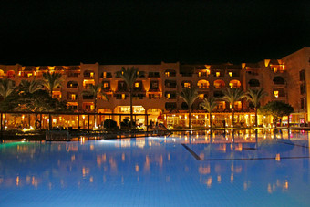 赫尔加达埃及7月灯晚上酒店是反映了池水晚上明亮的灯度假胜地酒店赫尔加达旅行概念人放松晚上附近池池和晚上酒店假期人放松晚上附近池