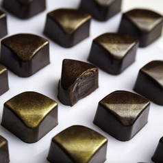 减少奢侈品巧克力手工制作的糖果糖果与巧克力酱装饰与金可食用的闪闪发光的白色背景独家手工制作的糖果