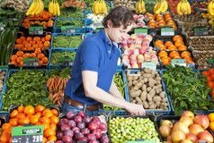 蔬菜水果商工作在各种各样的板条箱新鲜的水果而且蔬菜商店