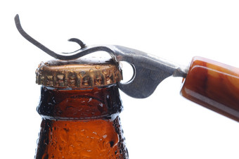 宏拍摄棕色（的）啤酒瓶与开瓶器准备好了撬的瓶帽水平格式在白色