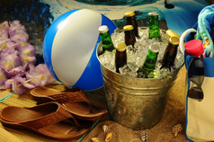 海滩仍然生活与温暖的下午阳光海滩球手提包乳液凉鞋太阳镜而且法律环绕桶各种各样的啤酒瓶冰