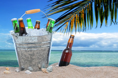 各种各样的啤酒瓶桶冰的沙子热带海滩一个啤酒瓶没有帽本身卡住了的沙子下一个的桶