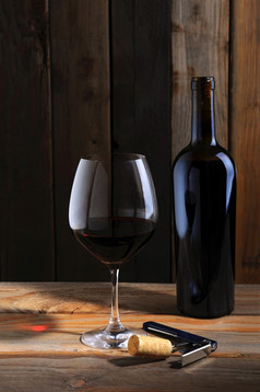 单瓶红色的酒而且葡萄酒杯乡村酒地窖设置定向光与酒玻璃反射表格前