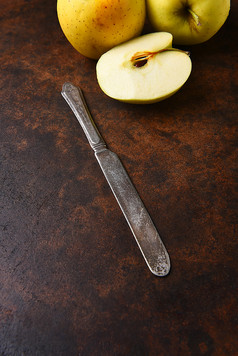 特写镜头老刀与金美味的苹果的背景垂直格式黑暗斑驳的表面