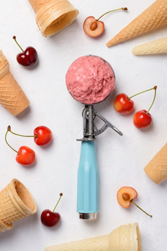樱桃冰奶油独家新闻勺子与华夫格视锥细胞和成熟的新鲜的樱桃白色表格平铺