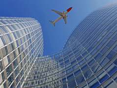飞机飞行在现代办公室玻璃摩天大楼