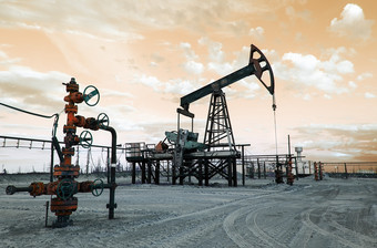 石油泵杰克和井口与阀电枢在日落的油田提取石油石油和气体概念健美的