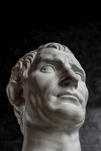 白色石膏复制古老的雕像的家伙朱利叶斯凯撒屋大维八月头为艺术家黑暗变形背景石膏雕塑男人。脸石膏复制古老的雕像八月头黑暗变形背景石膏雕塑男人。脸