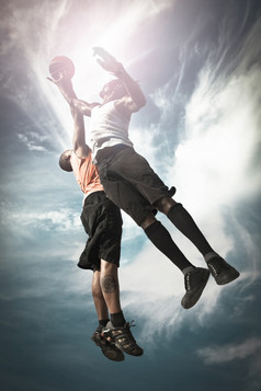两个篮球球员玩街篮子和跳在一起抓的球