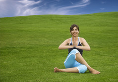 美丽的运动女人使瑜伽美丽的绿色草地