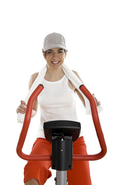 年轻的女人培训锻炼自行车的健身房
