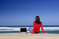 女人工作与移动PC的海滩