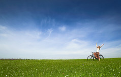 快乐年轻的女人与古董自行车绿色草地